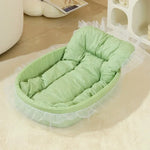 Green pastel pet nest with a padded base, raised sides and decorative lace trim.